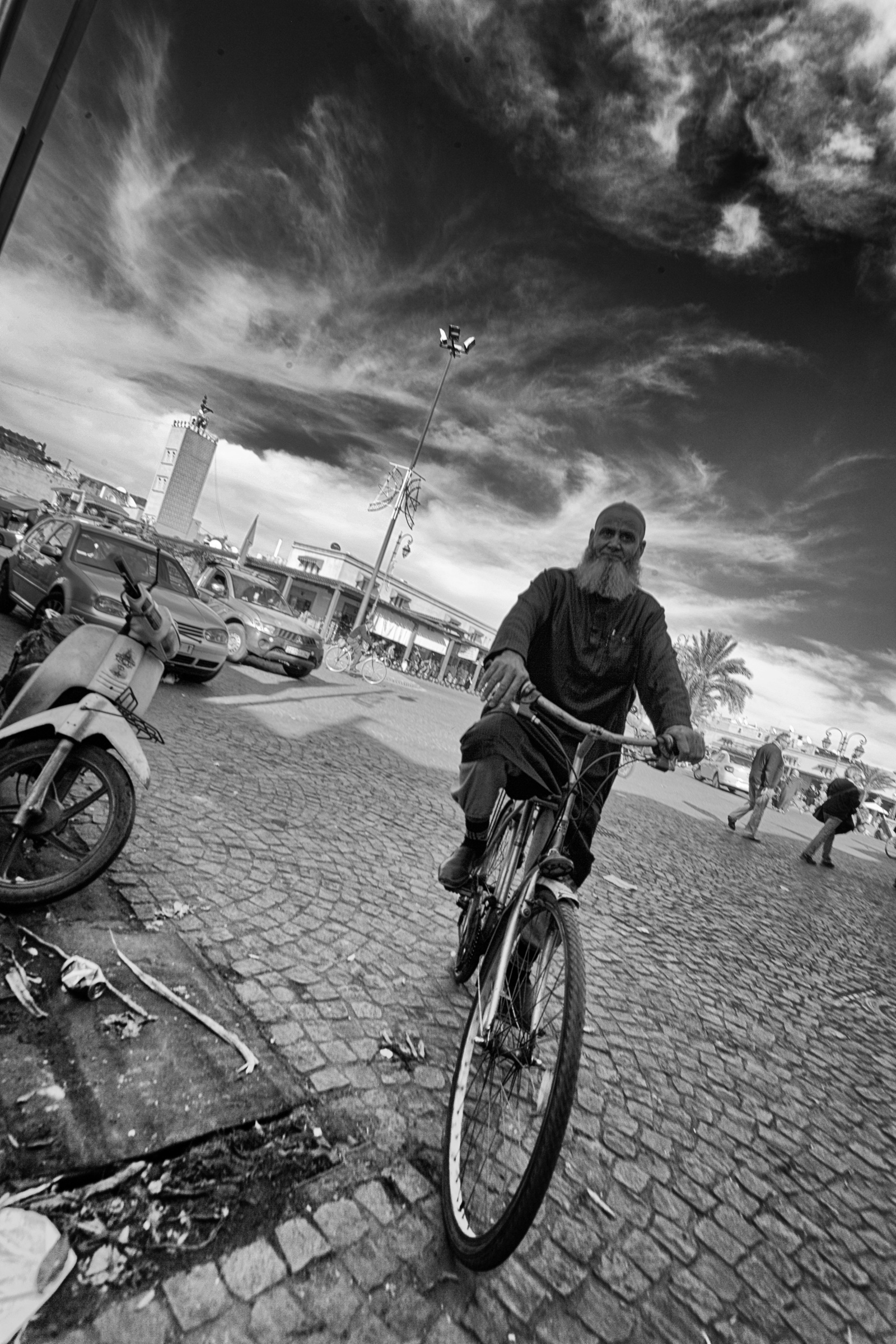 Hombre en bicicleta en una plaza de Marrakech bajo un cielo nublado